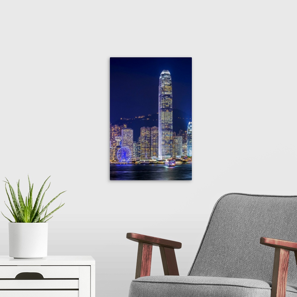 A modern room featuring Hong Kong skyline, IFC Tower and skyscrapers on Hong Kong Island at night seen from Tsim Sha Tsui...