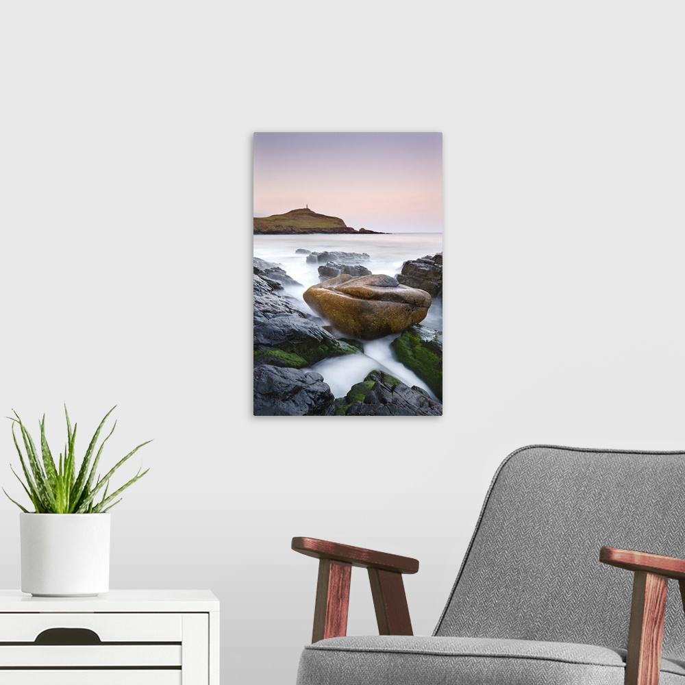 A modern room featuring Huge granite boulder lodged on the shores of Porth Ledden at dawn, Cornwall, England. Spring, Apr...