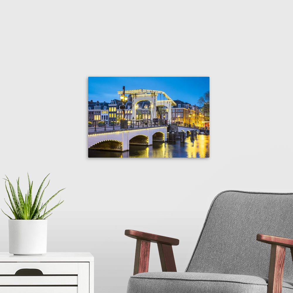 A modern room featuring Netherlands, North Holland, Amsterdam. Magere Brug, Skinny Bridge, on the Amstel River at night.