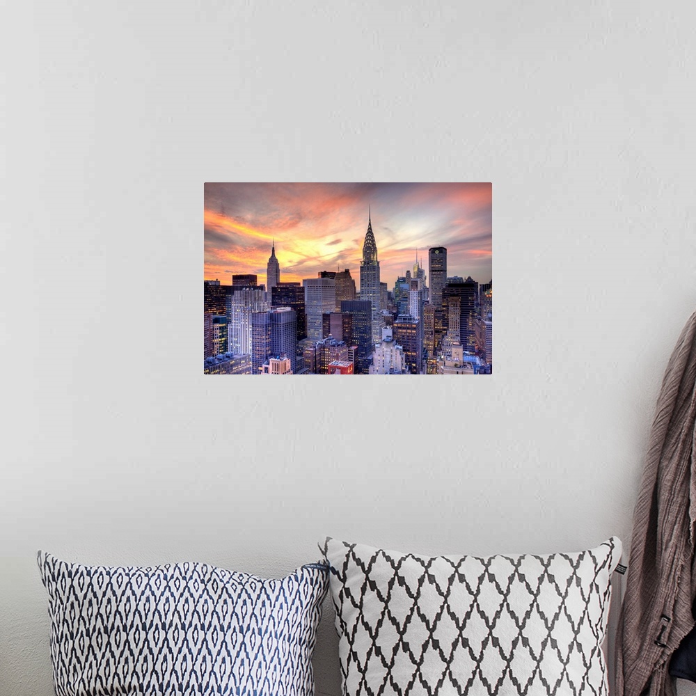 A bohemian room featuring Some of the large skyscrapers in Manhattan are pictured under a beautiful sunset sky.