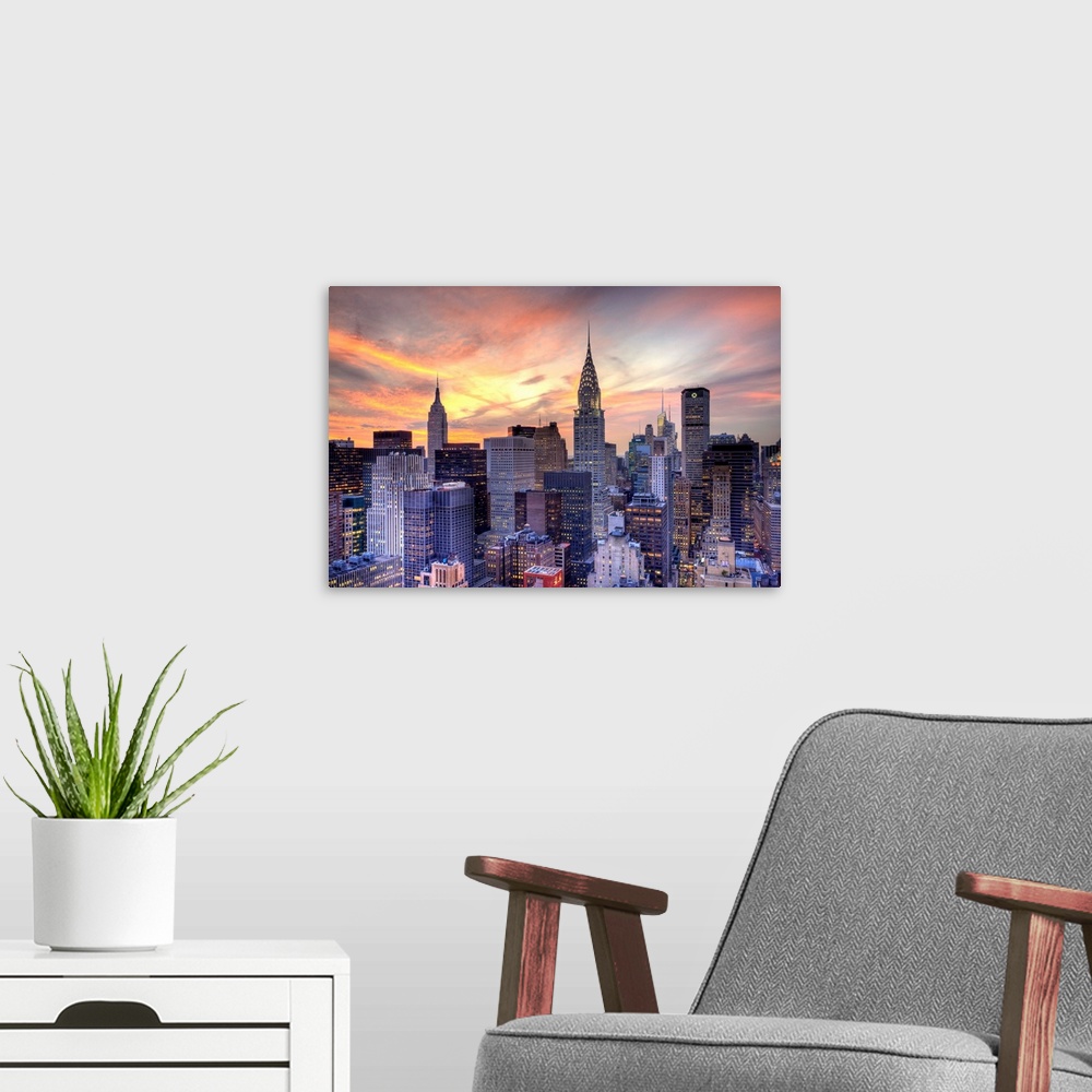 A modern room featuring Some of the large skyscrapers in Manhattan are pictured under a beautiful sunset sky.