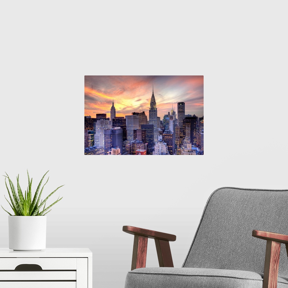 A modern room featuring Some of the large skyscrapers in Manhattan are pictured under a beautiful sunset sky.