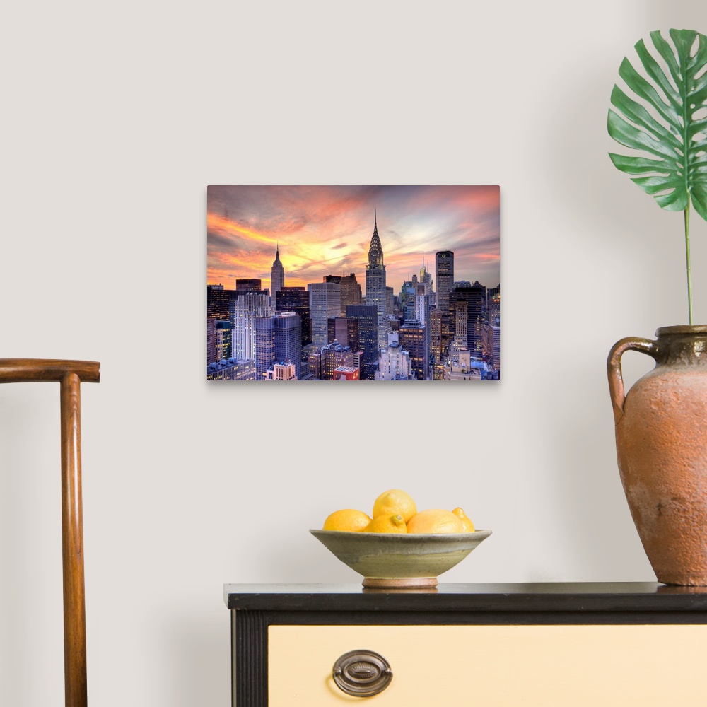 A traditional room featuring Some of the large skyscrapers in Manhattan are pictured under a beautiful sunset sky.