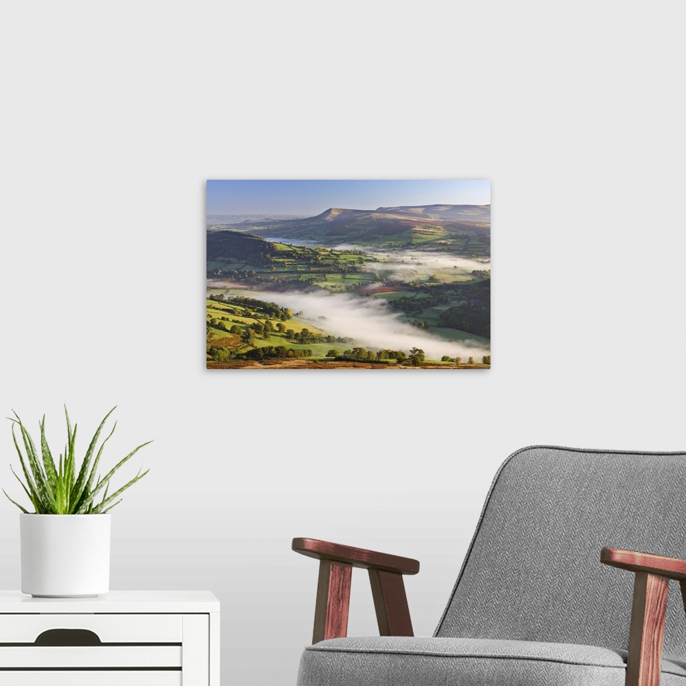 A modern room featuring Mist covered rolling countryside backed by the Black Mountains, Brecon Beacons National Park, Pow...