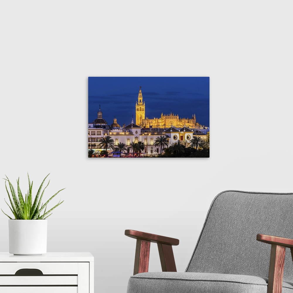 A modern room featuring Night view of city skyline with Cathedral and Giralda bell tower, Seville, Andalusia, Spain.