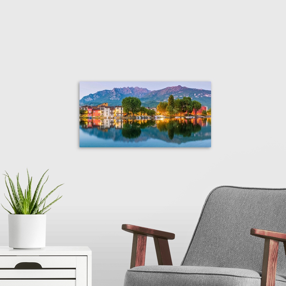 A modern room featuring Lecco, Lombardy, Italy. Panoramic view of the colorful houses and the Mount Resegone reflected on...