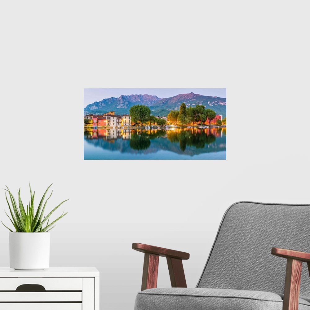 A modern room featuring Lecco, Lombardy, Italy. Panoramic view of the colorful houses and the Mount Resegone reflected on...