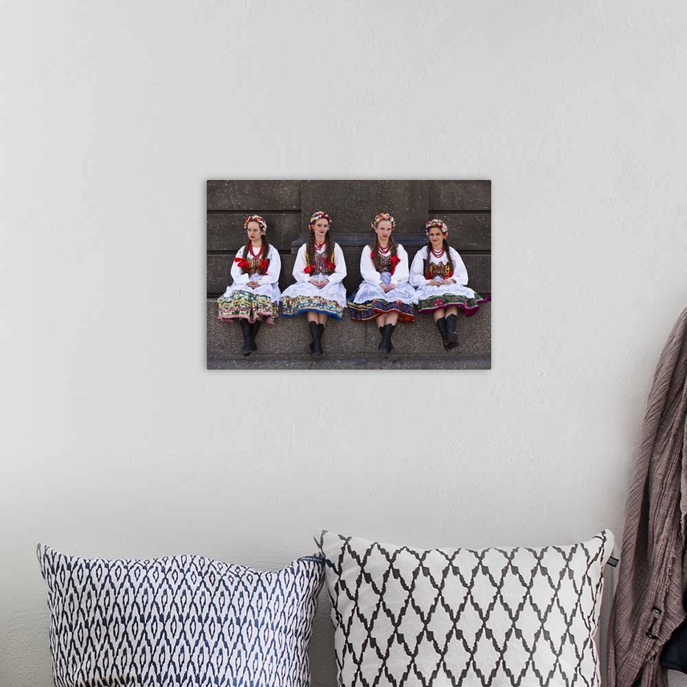 A bohemian room featuring Poland, Cracow. Polish girls in traditional dress sitting at the base of the statue of Adam Micki...