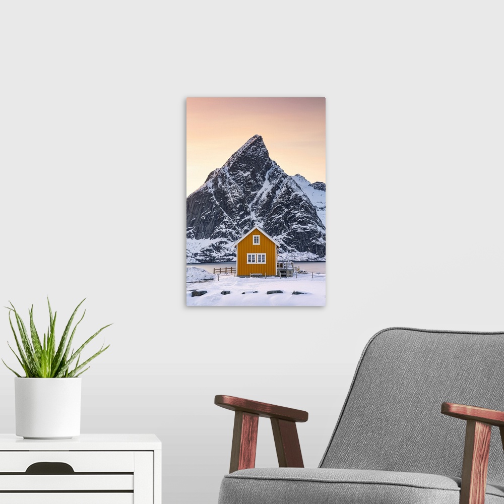 A modern room featuring Yellow Rorbu with majestic Olstind peak covered with snow on background, Sakrisoy, Reine, Nordlan...