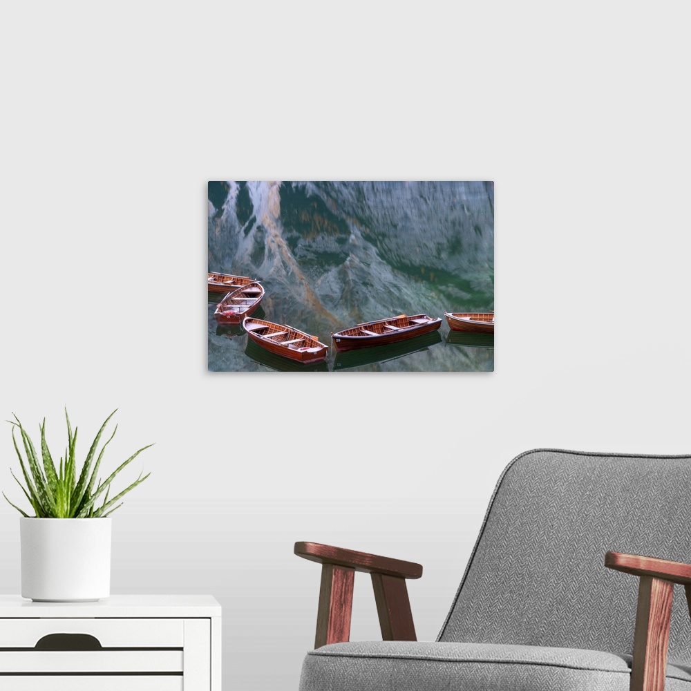 A modern room featuring Row boats floating in the Braies lake on a calm morning, with the mountains reflecting in the wat...