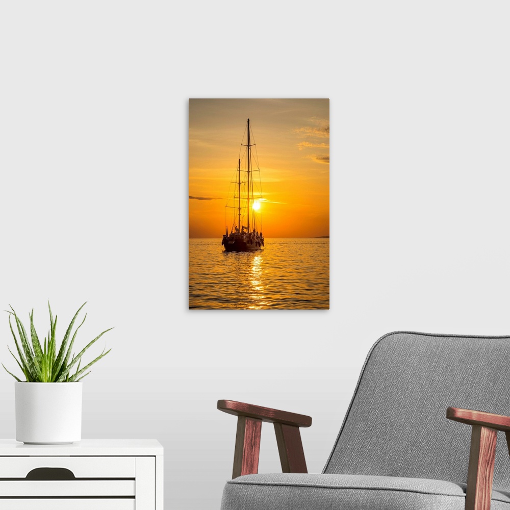 A modern room featuring Sailing boat at sunset, Mykonos Town, Mykonos, Cyclade Islands, Greece.