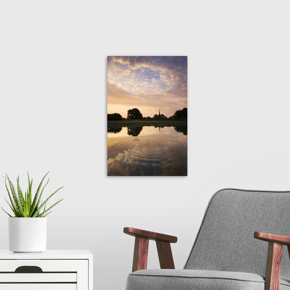 A modern room featuring Salisbury Cathedral Spire and a beautiful dawn sky reflected in a rippled pond, Salisbury, Wiltsh...