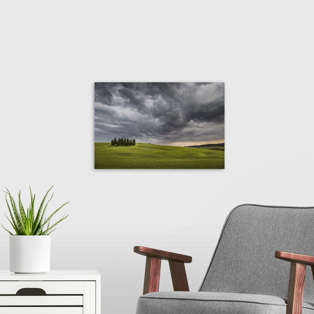 A modern room featuring San Quirico d'Orcia, Tuscany, Italy. Cypresses and stormy sky.