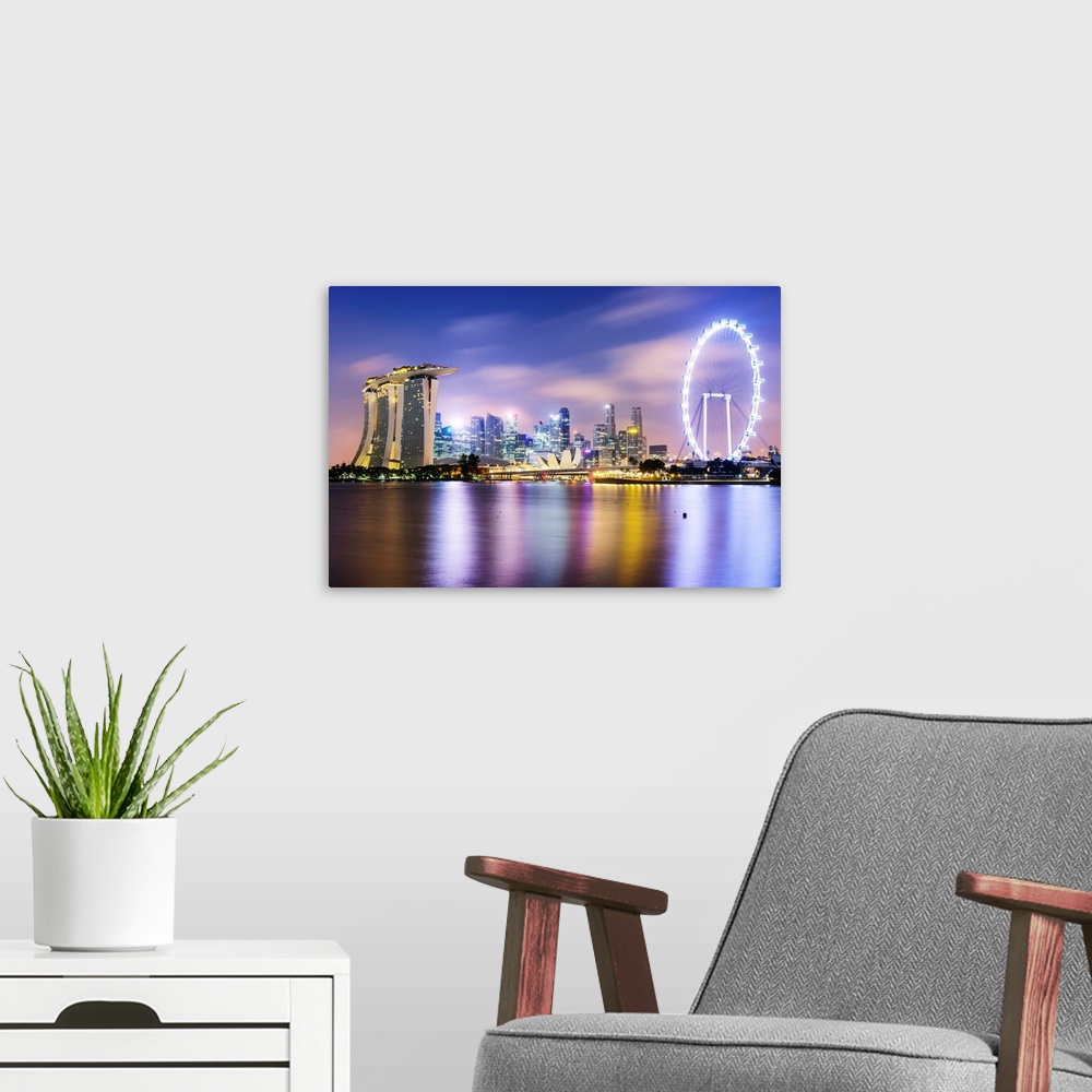 A modern room featuring Singapore skyline at night reflected in lake, Singapore.