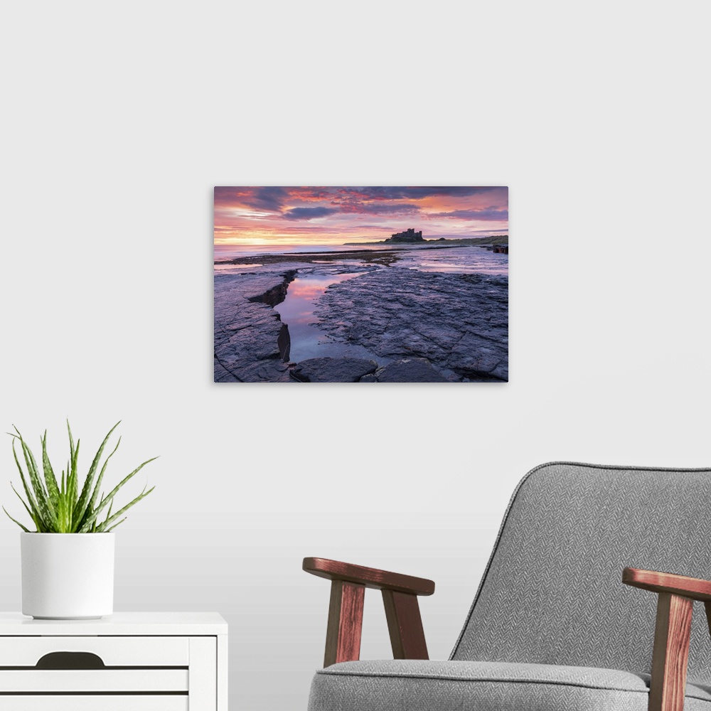 A modern room featuring Sunrise over Bamburgh Castle from the rocky shores of Bamburgh Beach, Northumberland, England. Au...