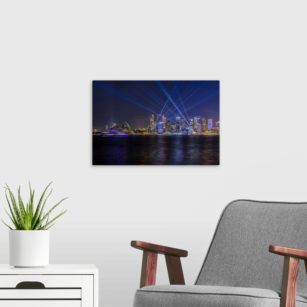 A modern room featuring Sydney Opera House and skyline illuminated with projections and lasers during Sydney Solstice cel...