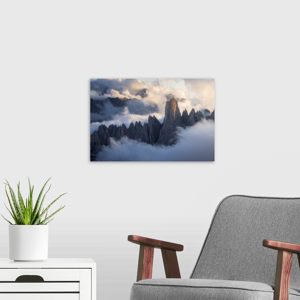 A modern room featuring The Cadini di Misurina emerging from the sea of clouds during a stormy late summer sunset. Dolomi...