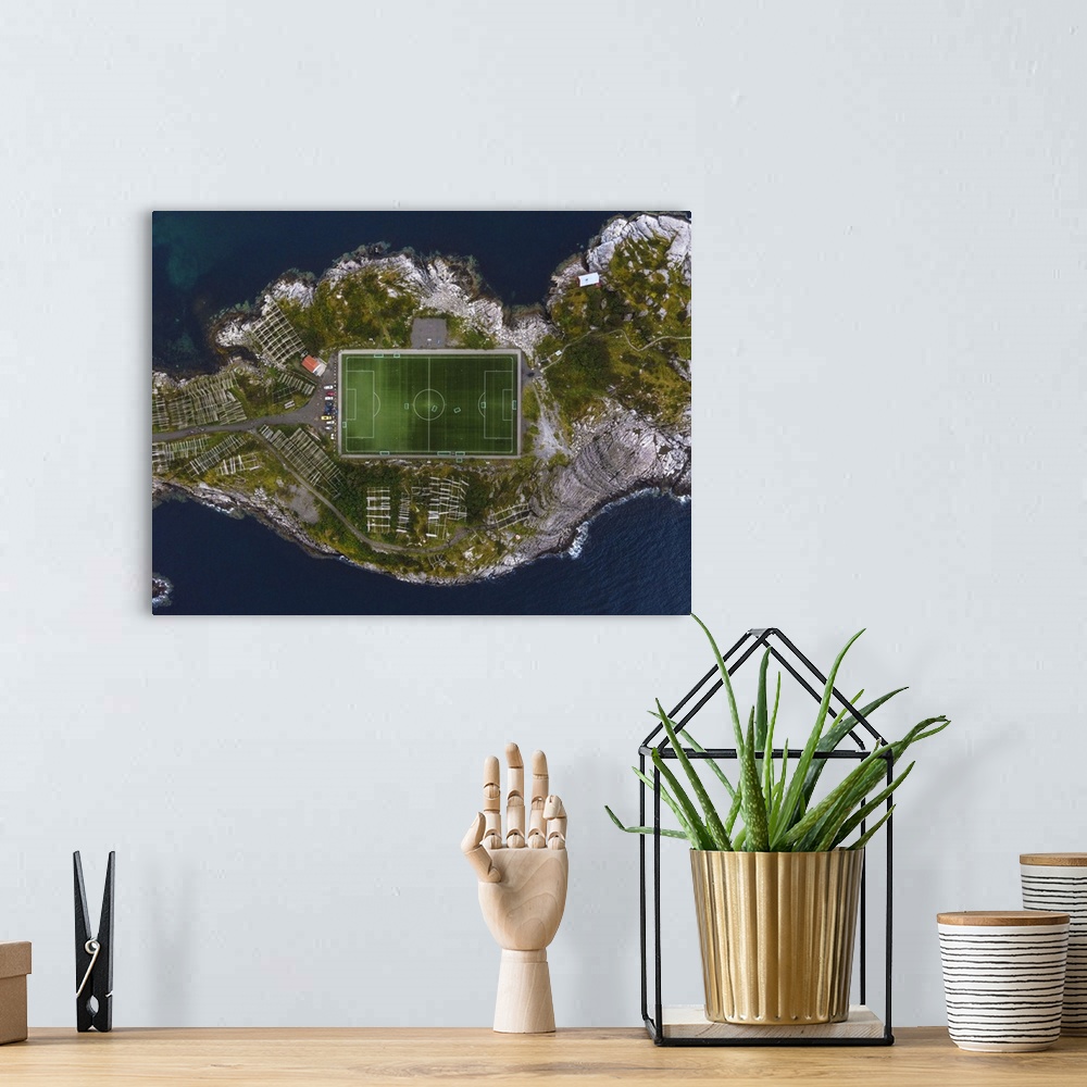 A bohemian room featuring The football field of Henningsvaer framed by the rocks of the coast. Lofoten Islands, Norway.