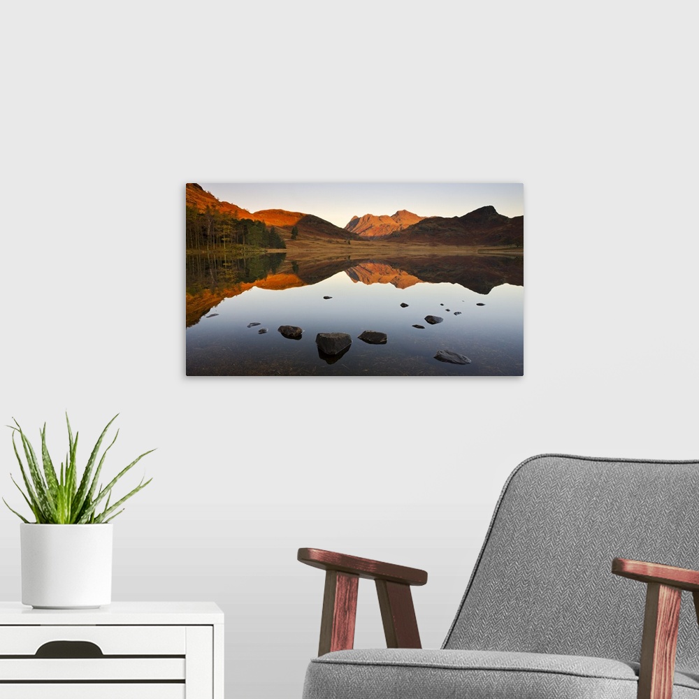 A modern room featuring The Langdale Pikes reflected in a mirrorlike Blea Tarn at sunrise, Lake District National Park, C...