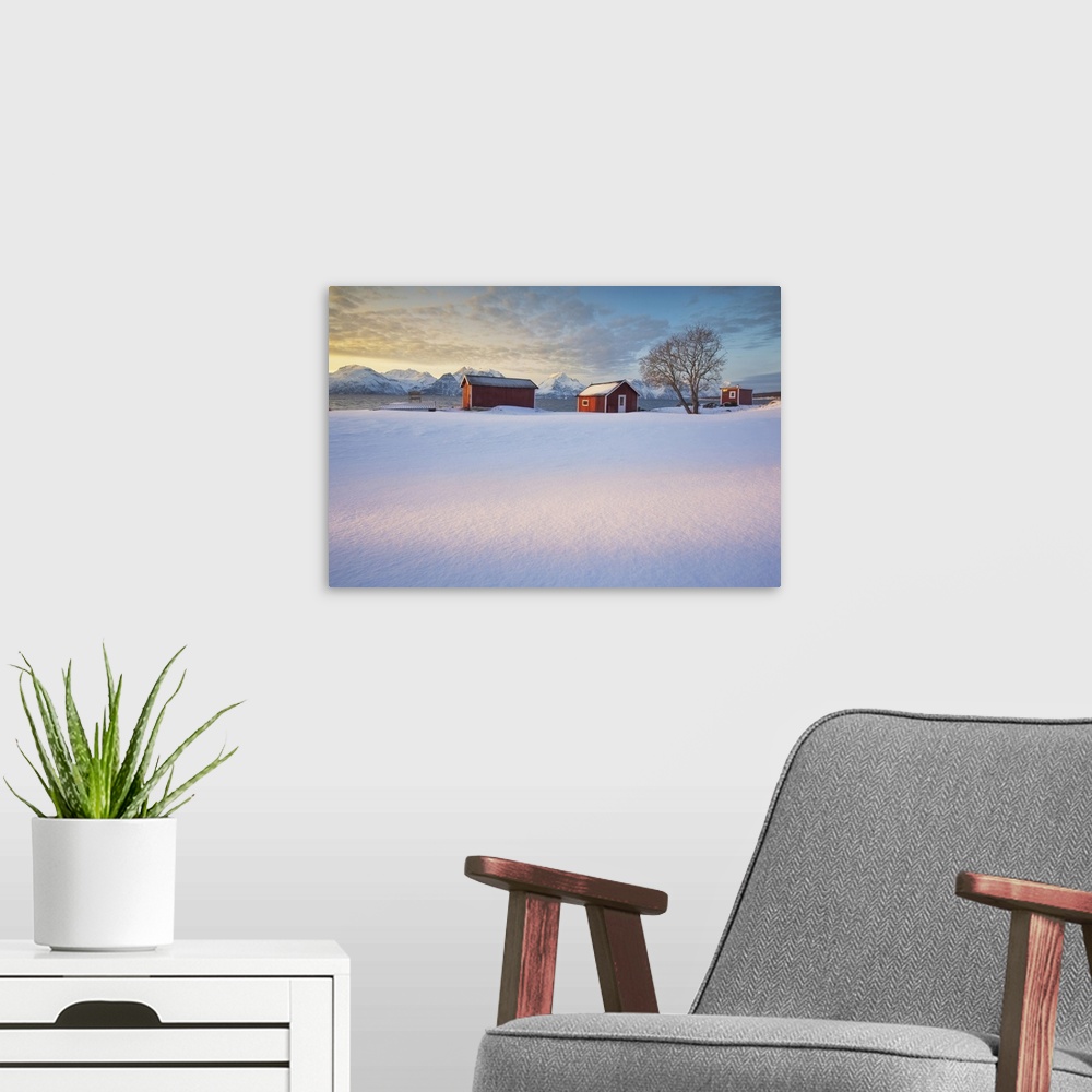 A modern room featuring The orange sky at sunset frame the frozen sea and typical Rorbu immersed in the snow Djupvik Lyng...