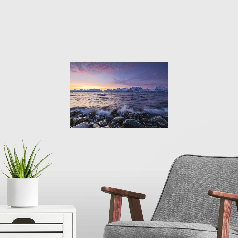 A modern room featuring The waves breaking on the stones beach during sunset. Nordmannvik, Kafjord, Lyngen Alps, Troms, N...