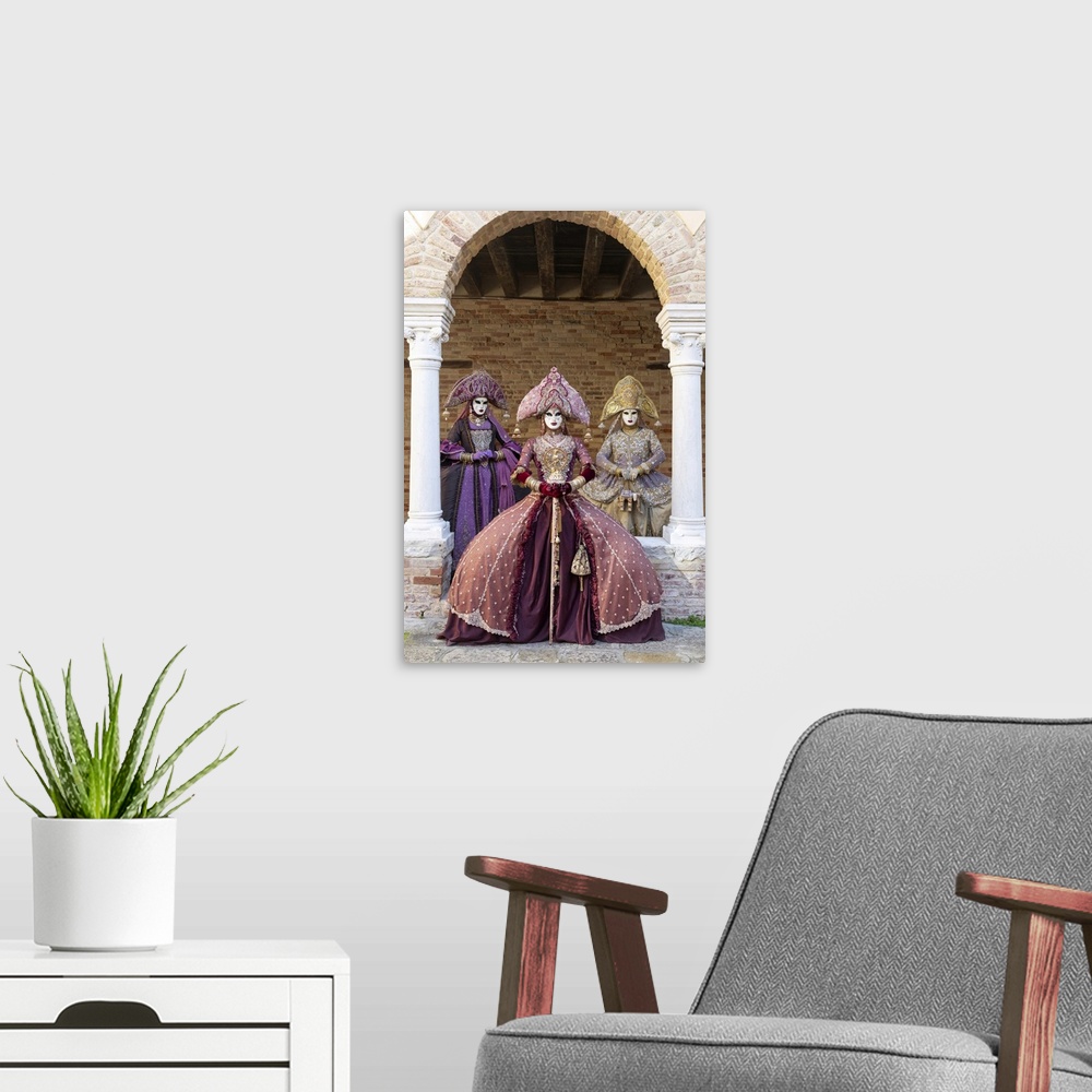 A modern room featuring Three women wearing Indian style costumes and masks pose in the cloisters of Chiesa di San France...