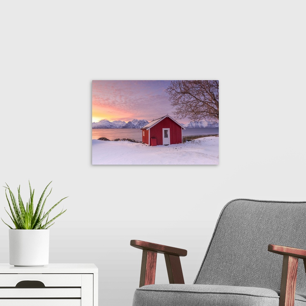 A modern room featuring Traditional Norwegian house during a sunset on the fjord. Nordmannvik, Kafjord, Lyngen Alps, Trom...