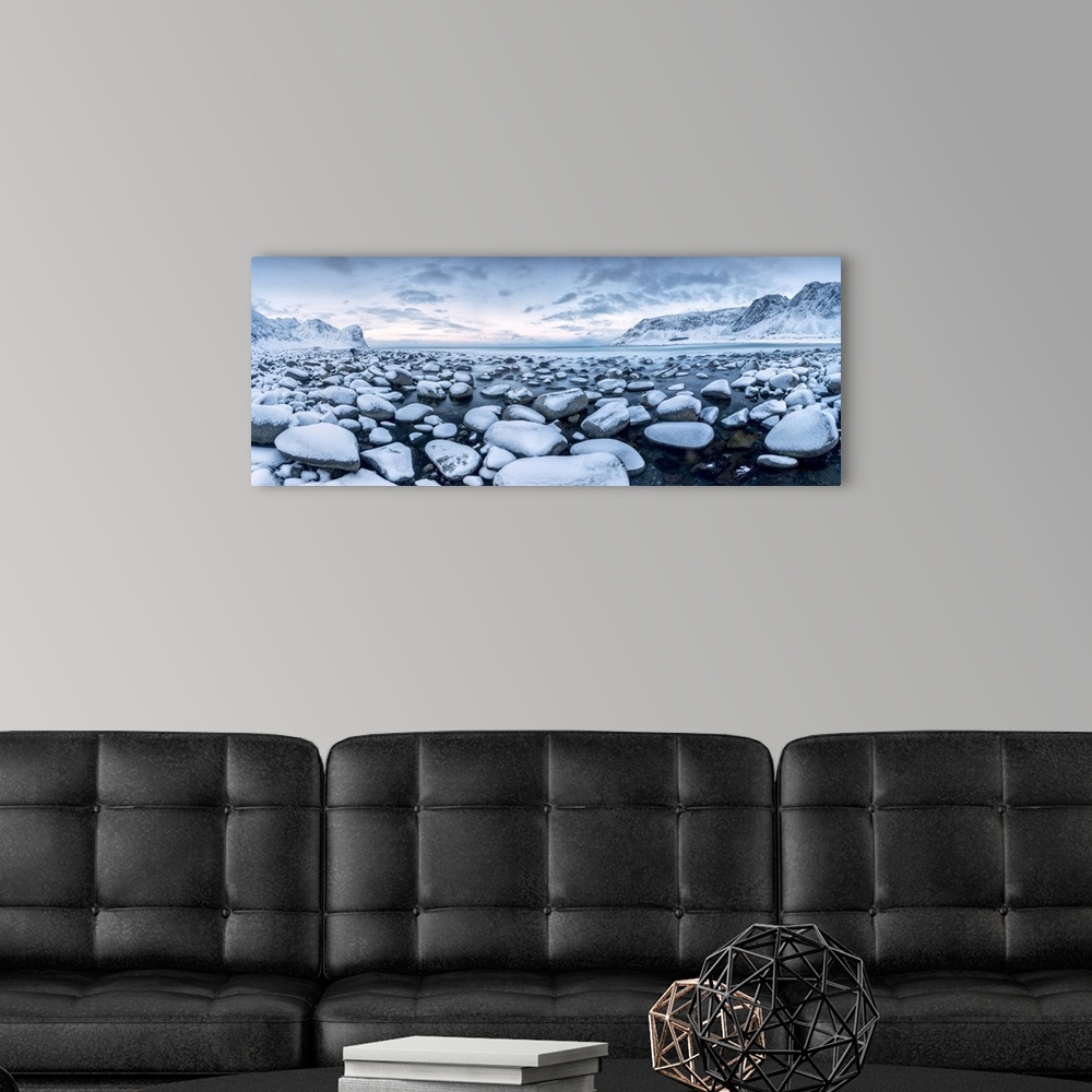 A modern room featuring Rocks in the cold sea and snow capped mountains under the blue light of dusk Unstad Lofoten Islan...