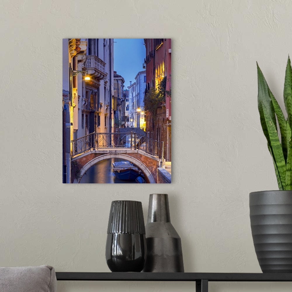 A modern room featuring Venice, Veneto, Italy. View over a bridge and a canal at dusk.