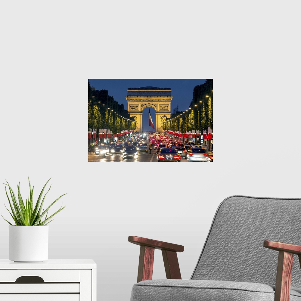 A modern room featuring View down the Champs Elysees to the Arc de Triomphe, illuminated at dusk, Paris, France.