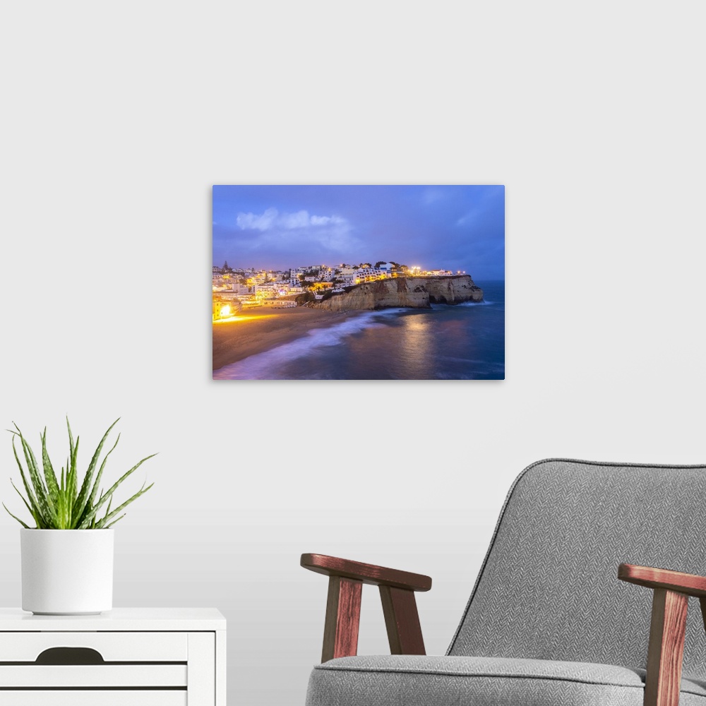 A modern room featuring View of the lights of the village of Carvoeiro and its beach at blue hour. Lagoa municipality, Al...