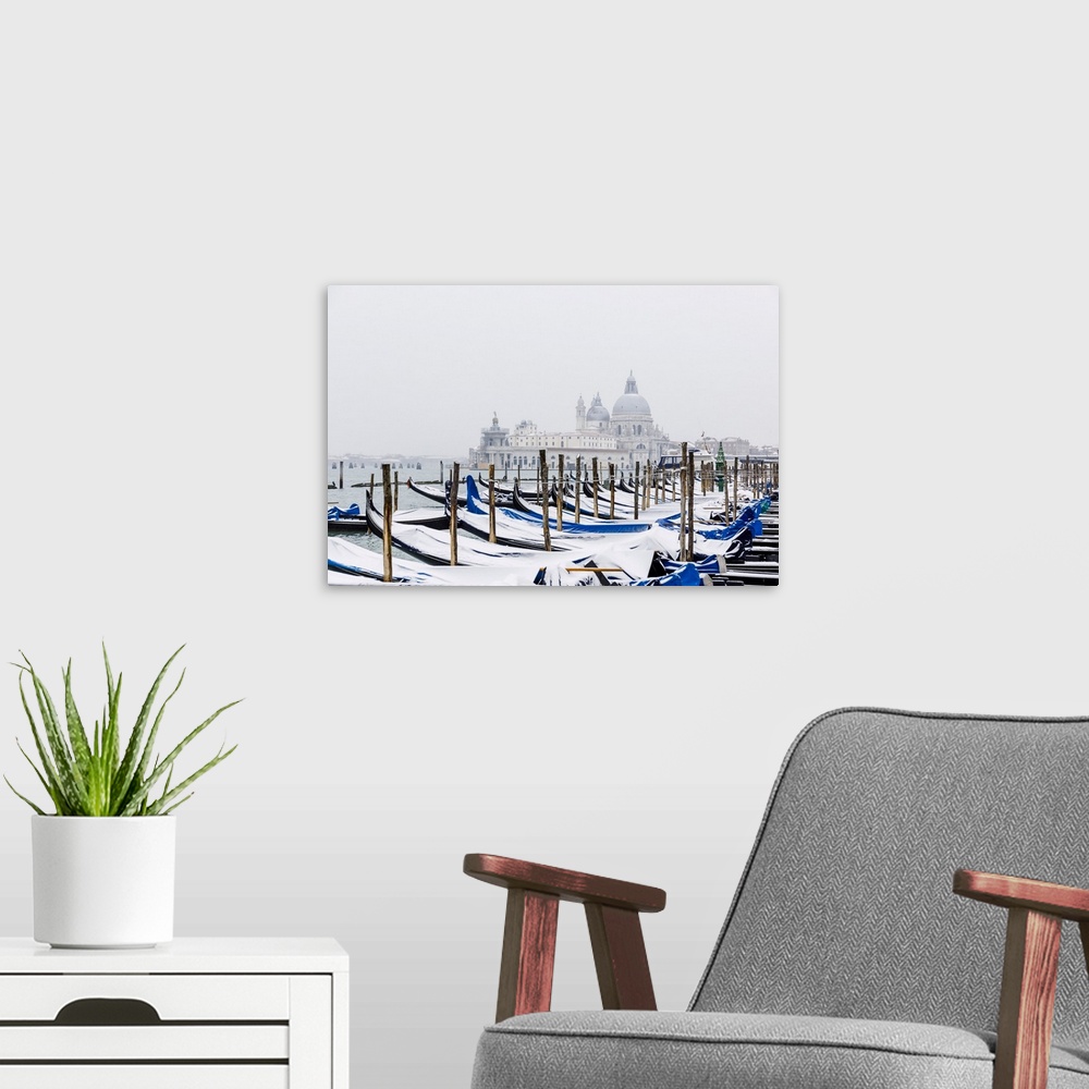 A modern room featuring Winter snowfall in the city of Venice, gondolas covered by snow and in the background the church ...