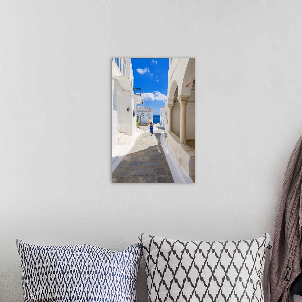A bohemian room featuring Young woman walking on the street that leads to the Church of St. Barbara, Andros, Cyclades archi...