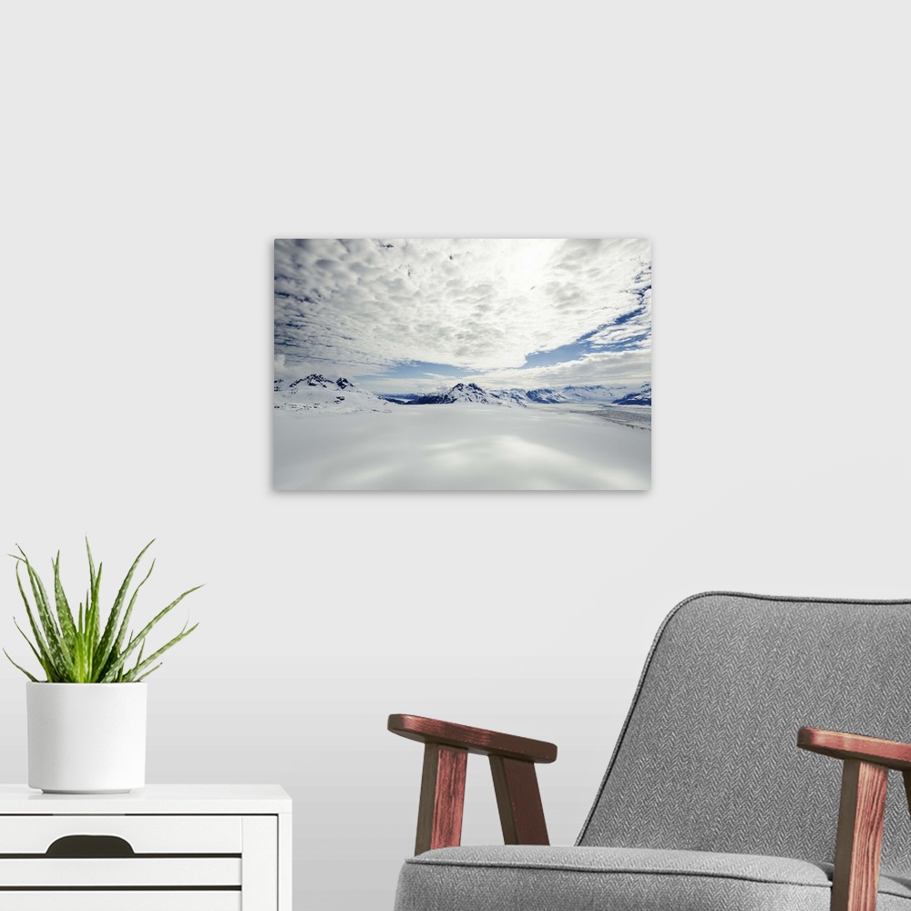 A modern room featuring A landscape covered in snow high in the mountains of Alaska, under a cloudy sky.