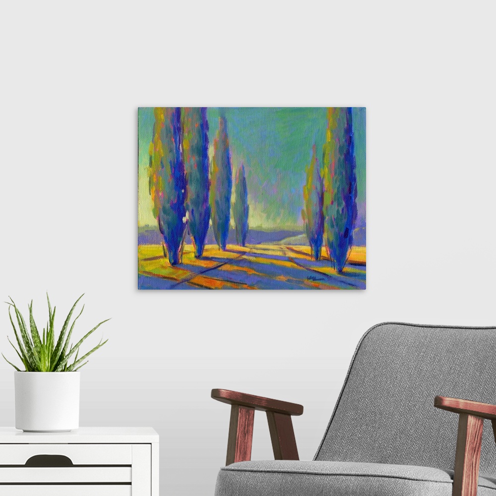 A modern room featuring Contemporary painting of tall, skinny trees in a field with pink and yellow sunset colors shining...