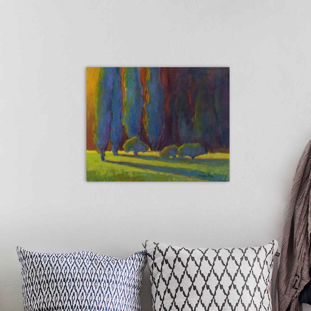 A bohemian room featuring Horizontal painting of a row of trees in shades of blue, orange and green.