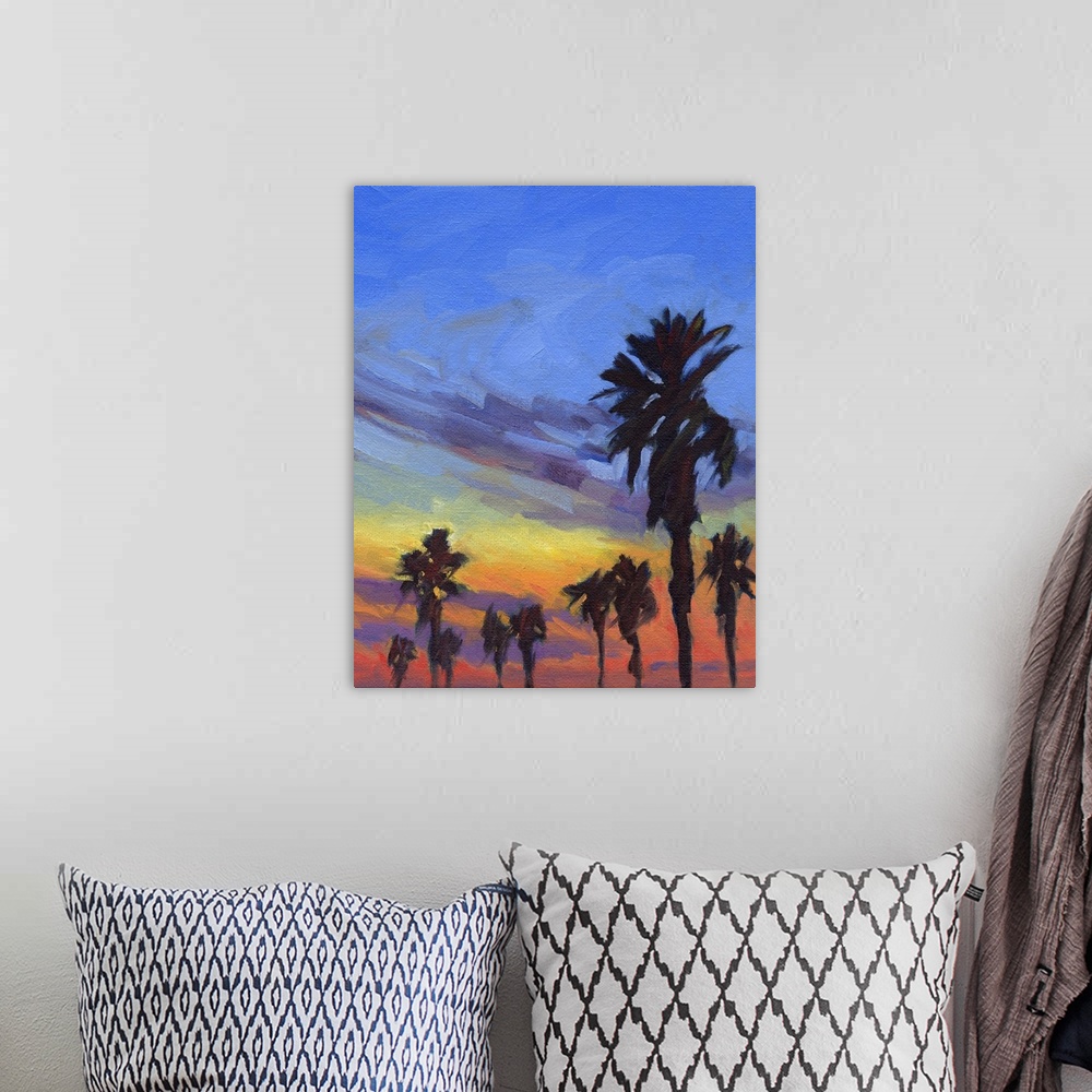 A bohemian room featuring A vertical painting of palm trees during a sunset.