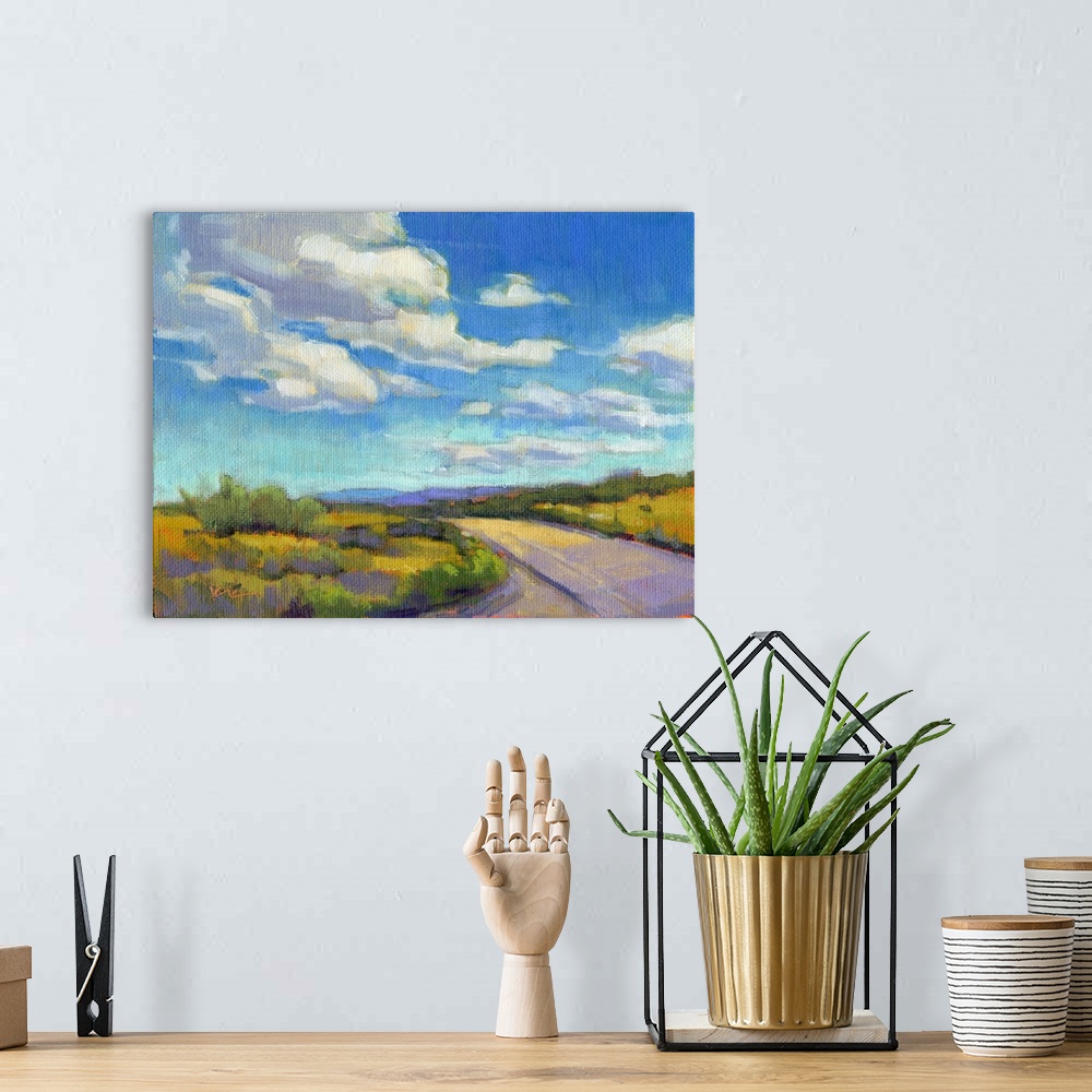 A bohemian room featuring Contemporary landscape painting of a road going through green fields with clouds and a blue sky a...