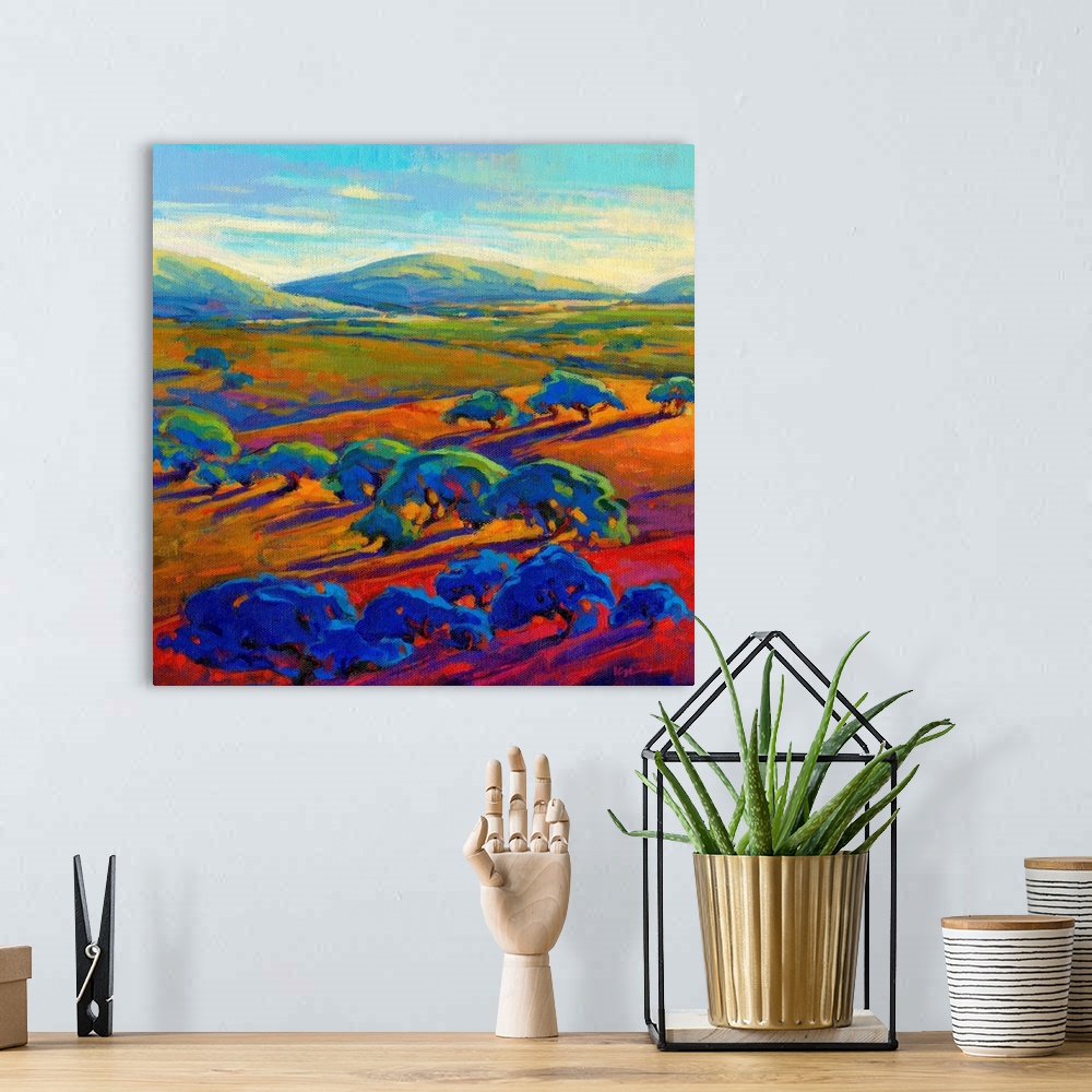 A bohemian room featuring A square contemporary painting of a row of trees and rolling hills in vibrant colors.