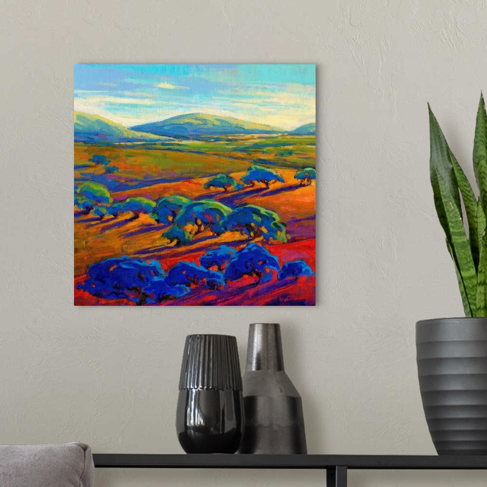 A modern room featuring A square contemporary painting of a row of trees and rolling hills in vibrant colors.