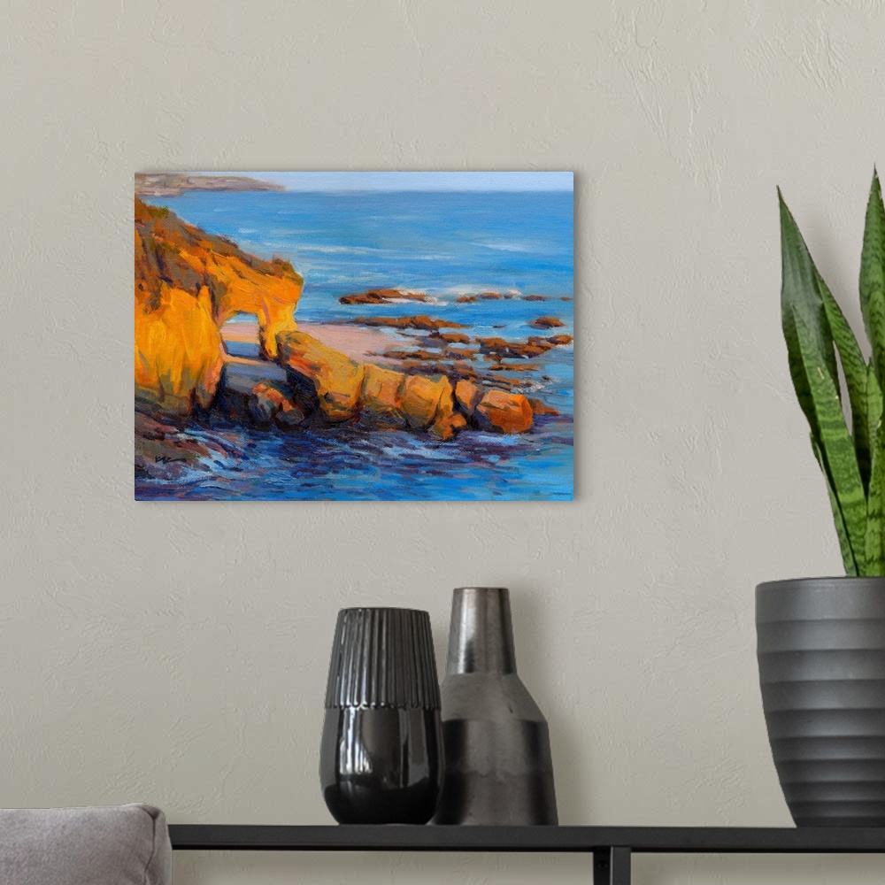 A modern room featuring Horizontal contemporary painting of a rocky cliff and a beach with vivid blue water.