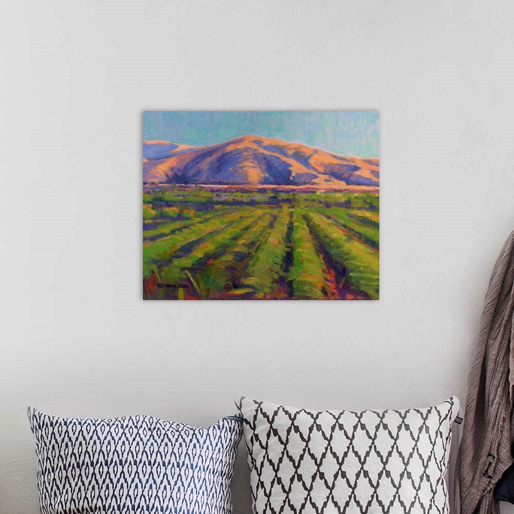 A bohemian room featuring A contemporary painting of fields with mountains in the background.