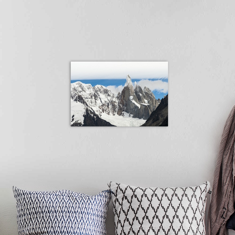 A bohemian room featuring Photograph of snow-covered mountain spires in South America surrounded thick fluffy clouds.