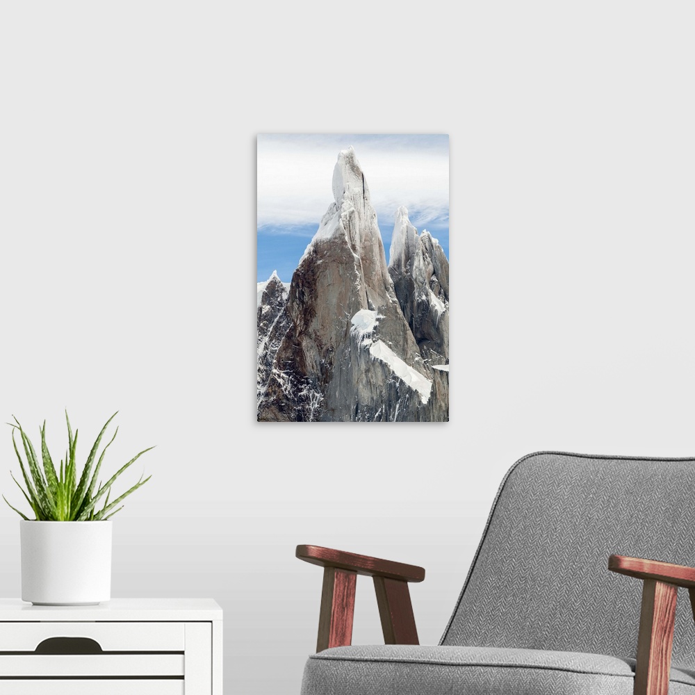 A modern room featuring Photograph of snow-covered mountain spires in South America surrounded thick fluffy clouds.