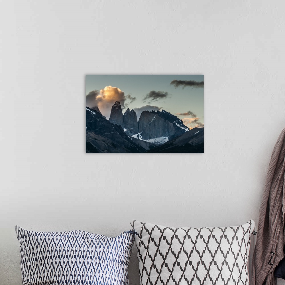 A bohemian room featuring Photograph of mountain spires in South America cast in shadow, with illuminated clouds in the sky.