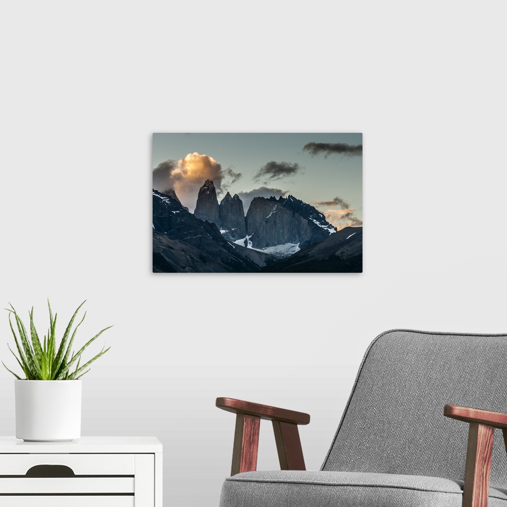 A modern room featuring Photograph of mountain spires in South America cast in shadow, with illuminated clouds in the sky.
