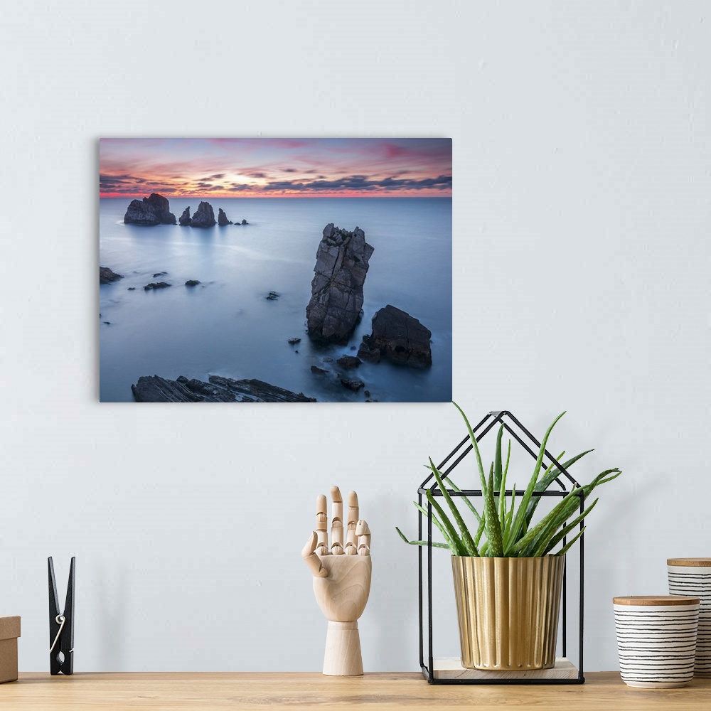 A bohemian room featuring Photograph of clouds and ocean boulders casting silhouettes from the sun setting in the distance.