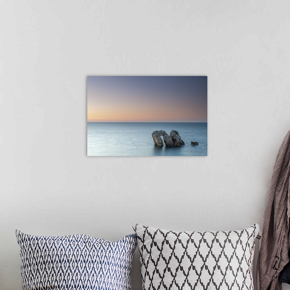 A bohemian room featuring Archway boulders in a blue ocean at sunset.