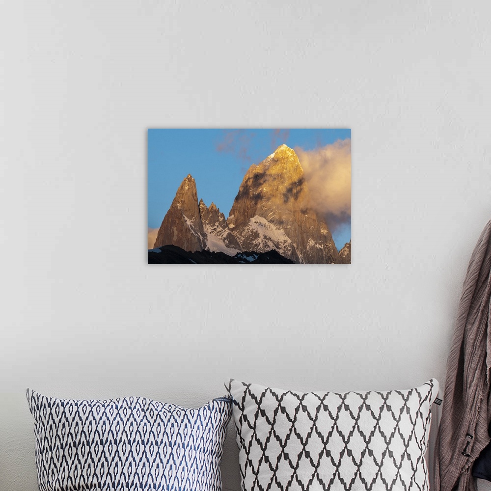 A bohemian room featuring Photograph of mountain spires in South America, with clouds moving in to the frame of the image.