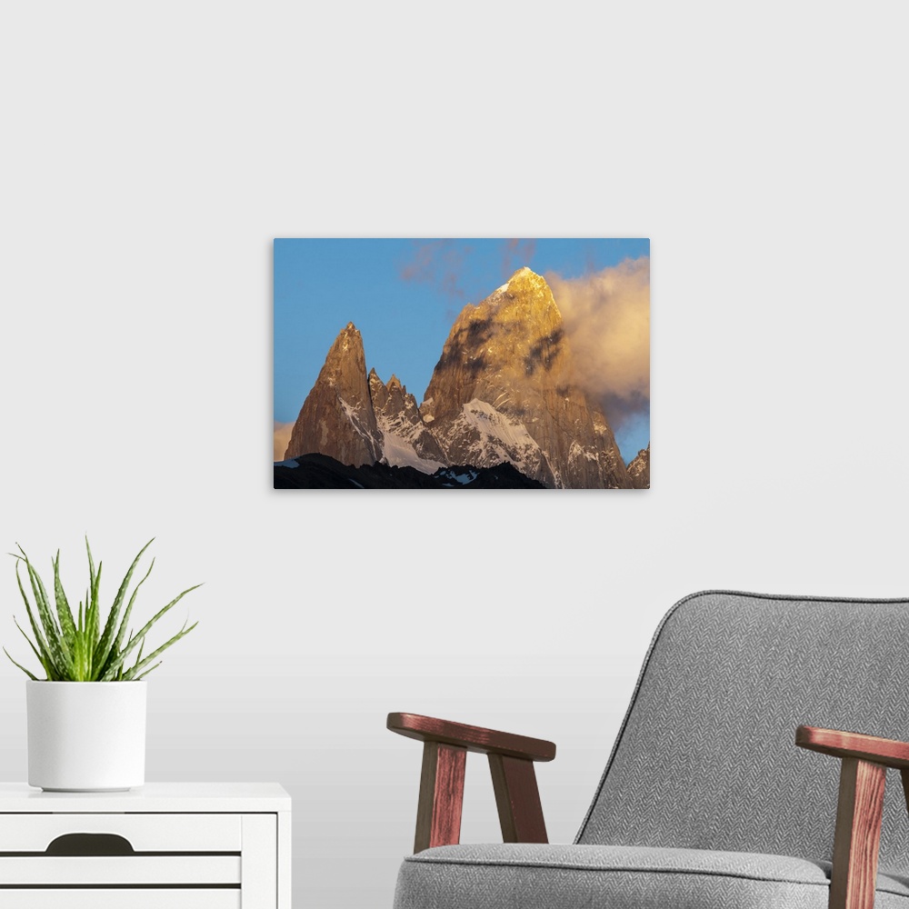 A modern room featuring Photograph of mountain spires in South America, with clouds moving in to the frame of the image.